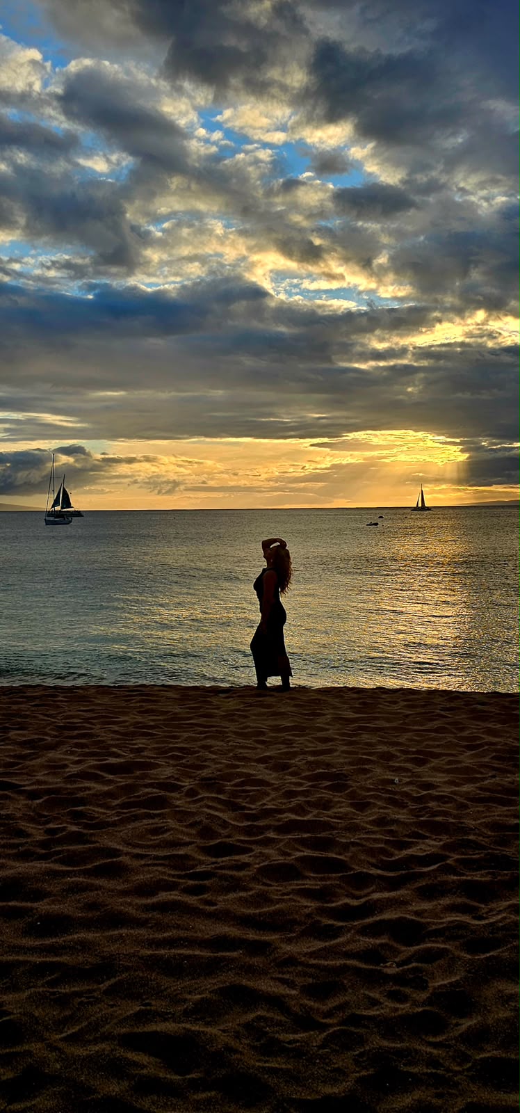 Sailboats on the ocean at sunset, seen from the beach