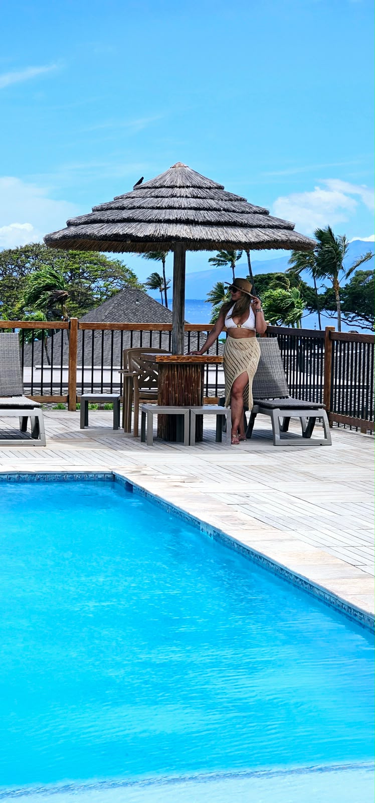 Maui Eldorado resort pool with a thatched umbrella, lounge chairs and palm trees
